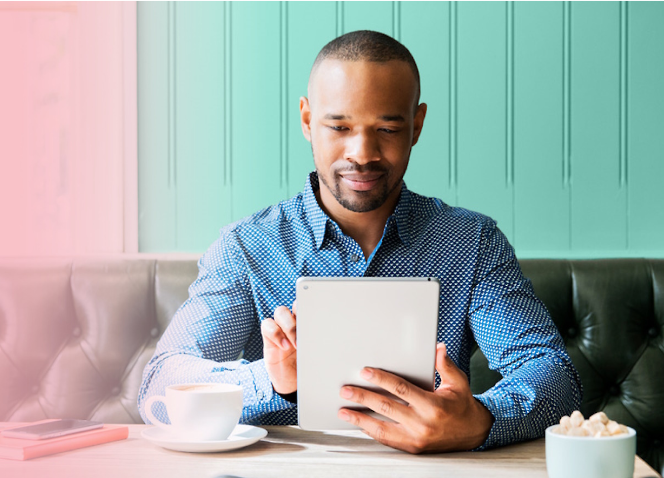 Una persona seduta che usa il tablet con il caffè sul tavolo