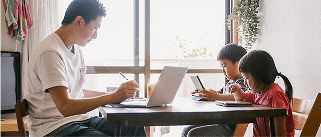 Una famiglia seduta a un tavolo mente usa un portatile.