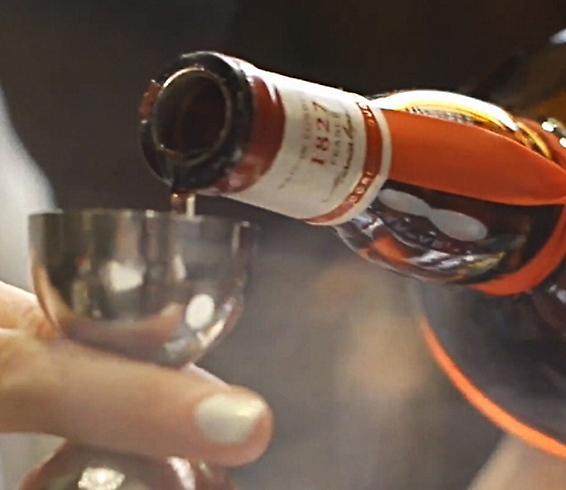 Una persona che versa liquore da una bottiglia in un bicchiere.