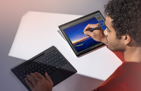 Una persona utilizza una tastiera Surface Pro Flex Keyboard scollegata e una Slim Pen per ritoccare una foto su un dispositivo Surface Pro.
