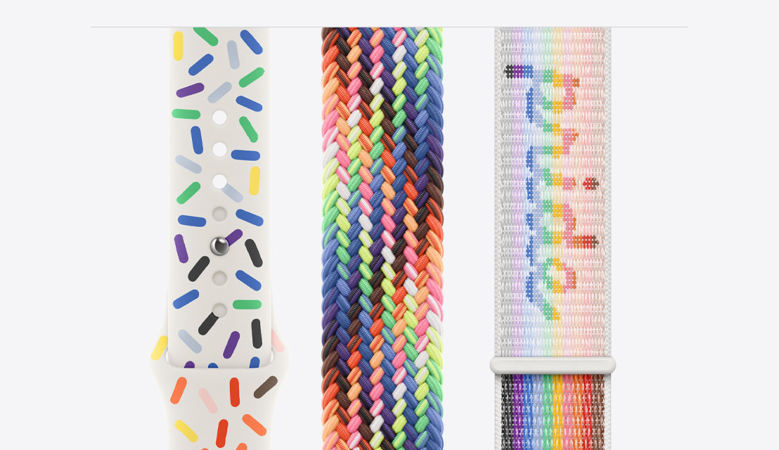 Tre cinturini per Apple Watch appoggiati su un piano: il cinturino Sport Pride Edition a sinistra, il nuovo cinturino Solo Loop intrecciato Pride Edition al centro e il cinturino Sport Loop Pride Edition a destra.